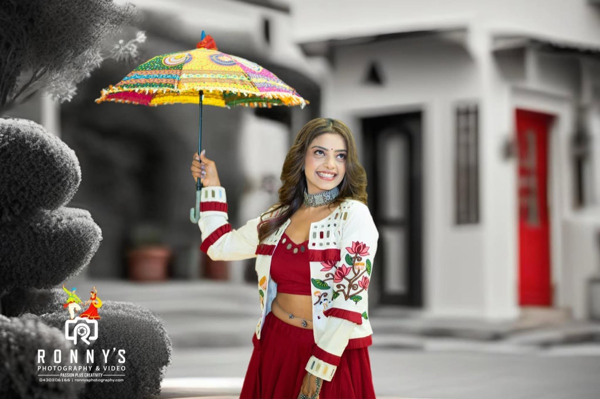 A woman in a red and white festive outfit holding a colourful umbrella